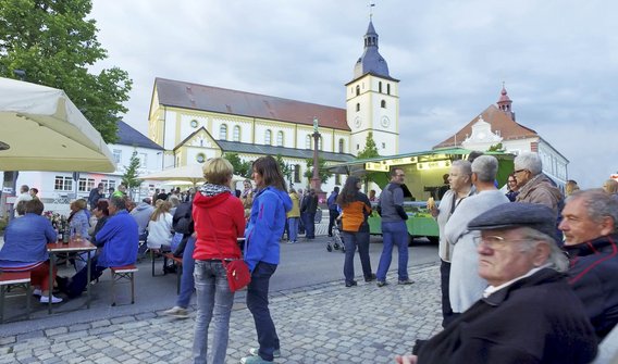 Bild: Menschen auf dem Marktplatz in Mitterteich bei einem Fest. Im Hintergrund ist die Kirche zu sehen.