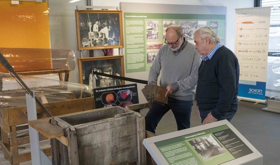 Bild: Zwei Männer, die im Museum in Mitterteich stehen und sich einige Stücke ansehen.